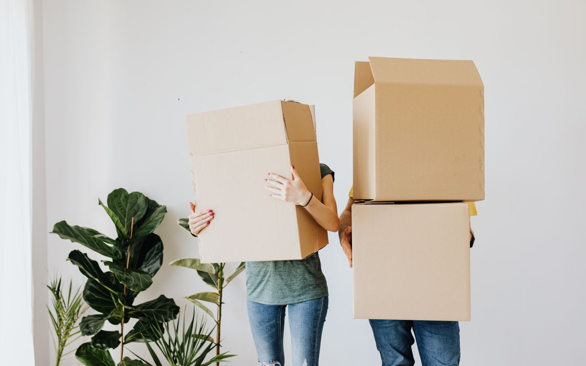 A couple carrying moving boxes into a new home